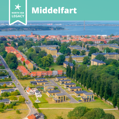 Aerial photo of Middelfart city with the sea and a suspension bridge in the horizon.