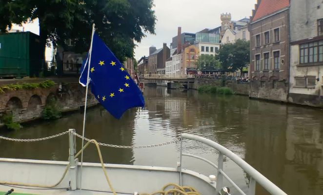 Boat sailing in a city carrying a large EU flag.