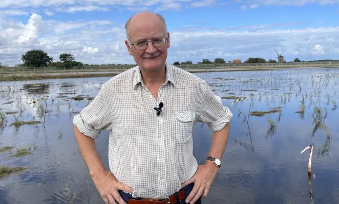 Man standing in front of a large wetland area with open water