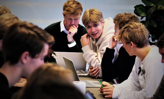 A group of school boys discussing around a table.