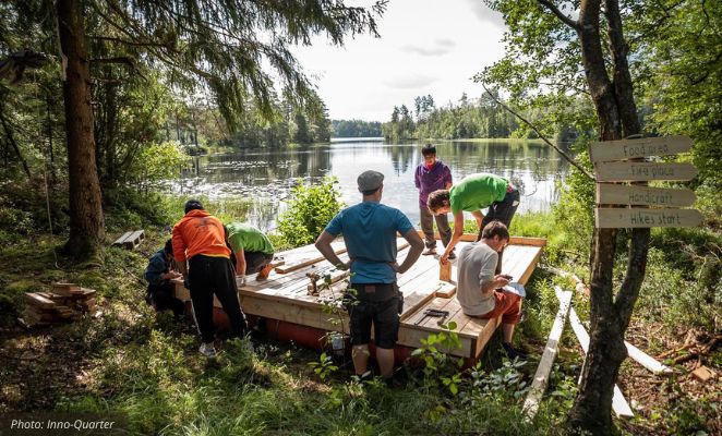 A group of festivalgoers constructing a wooden platform near a lake.