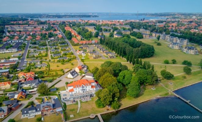 Aerial photo of Middelfart city with the sea and a suspension bridge in the horizon.
