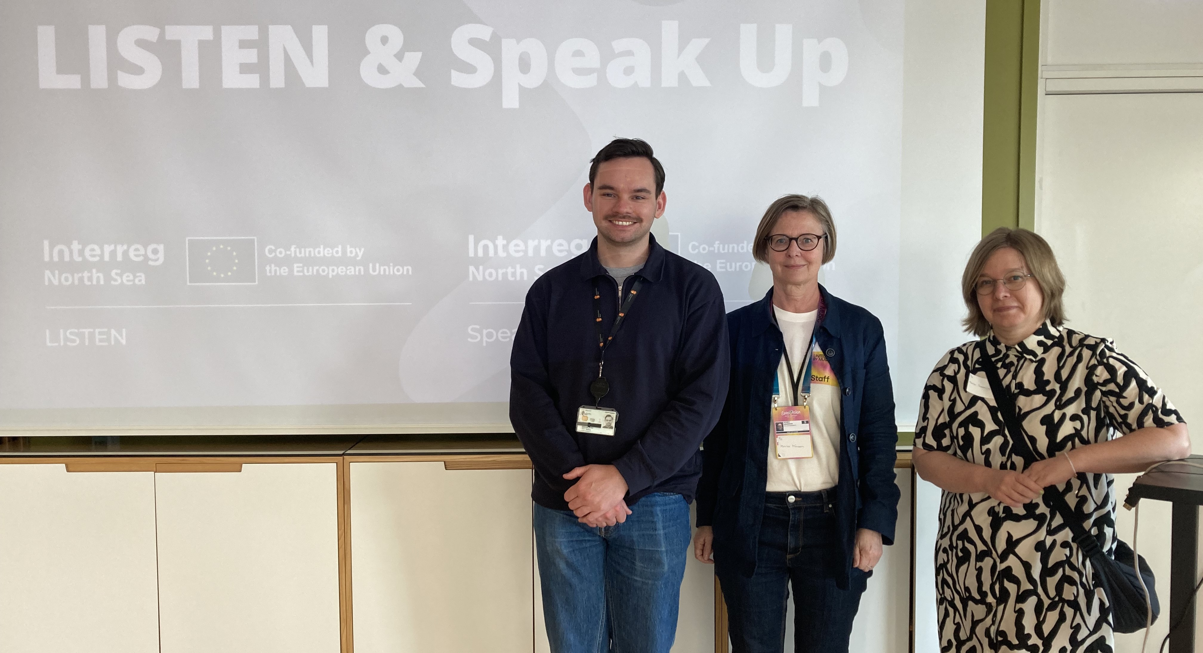 Three people standing in front of a presentation screen