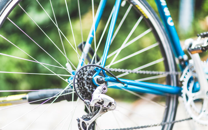 A closeup photo of the wheel of a blue bike.