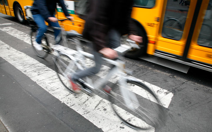 Cyclists wheeling past a yellow bus.