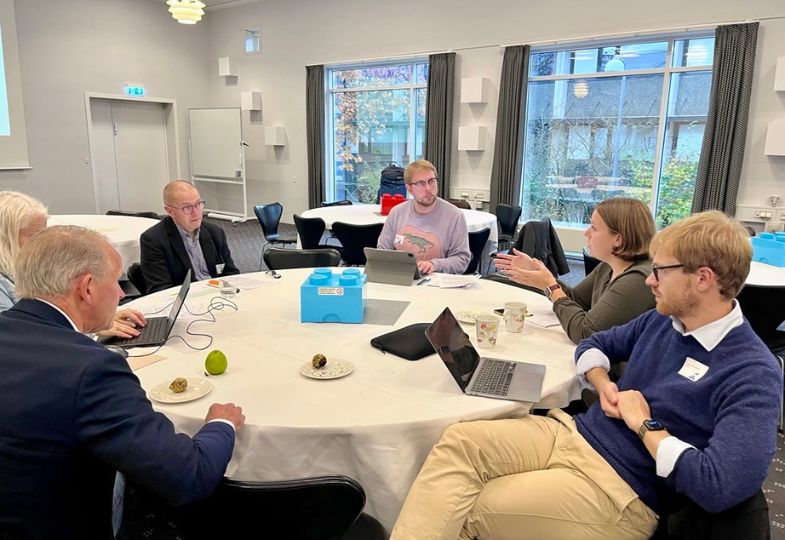 People seated around a roundtable in a light-filled room.