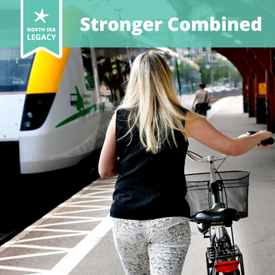 A young lady on a train platform pulling her bike towards a train.