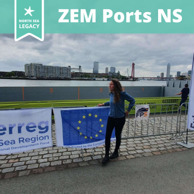 A young lady standing in a harbour, leaning against a large EU flag. 