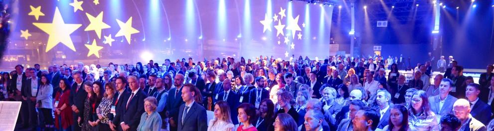 A large crowd gathered in front of a large blue veil with golden stars.