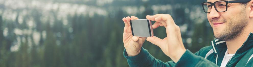 Man taking a photo outdoors in nature with his mobile phone.